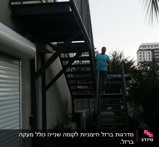 אדם עומד על מדרגות מתכת חיצוניות ליד מבנה